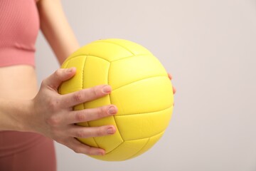 Woman with volleyball ball on light background, closeup. Space for text