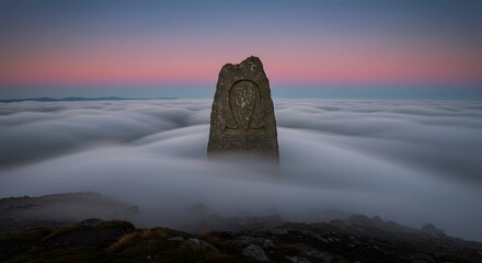 Ancient standing stone monument emerging from a thick blanket of fog at dramatic sunrise or sunset