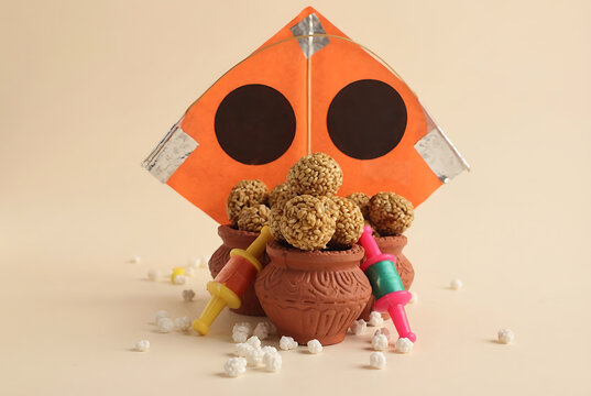 Traditional sesame seed sweet balls or til laddu in clay pots with orange kite for happy makar sankranti and pongal food concept photo