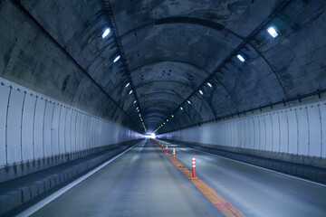 Obraz premium 光へ続く無人のトンネル、消失点のある静寂の道路