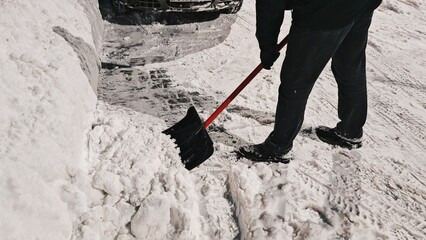 Clearing snow with a shovel in the winter on the street. a view of a person shoveling snow in the evening during winter