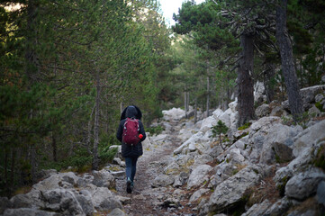Obraz premium Adventurous woman hiking over rocky terrain towards the Ibon de Plan glacial lake in the Pyrenees mountains of Spain