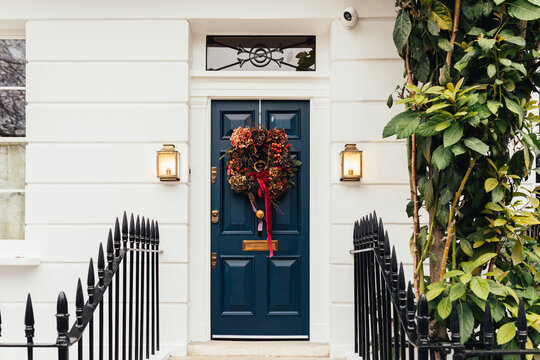 Dark blue front door with festive wreath and lantern lights in London. Concept of architecture and design.