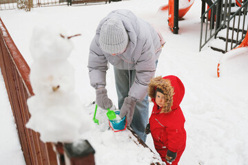 Snowman Creation with Child Playing in Snowy Park