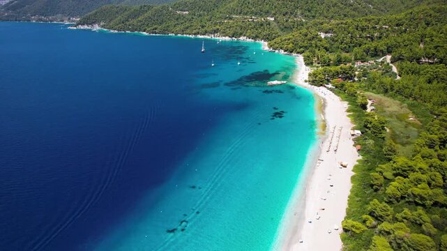 Panoramic aerial view of the long pebble beach of Milia and Panormos on Skopelos Island. High-quality 4K footage capturing the summer Mediterranean lifestyle