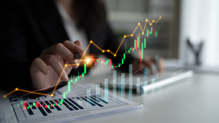 A business professional is focused on analyzing financial graphs and charts, showcasing an upward...