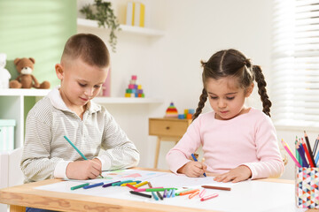 Fototapeta premium Children drawing with pencil and crayon at table indoors