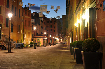 Evening quiet street of Camogli an old city with warm light of lanterns and colorful facades of houses, Italy