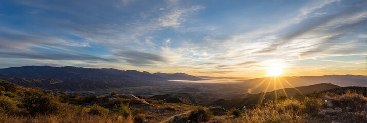 Panoramic sunrise over mountain valley with dramatic sky and golden light
