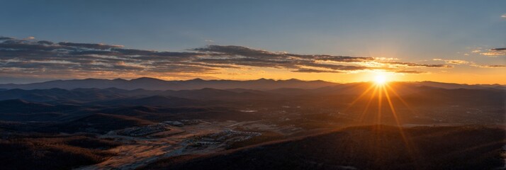 Majestic sunset over mountain range with golden horizon and soft clouds
