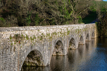 A timeless stone arch bridge reflects in a calm river. This serene landscape captures heritage and stability, perfect for travel, history and connection themed projects 