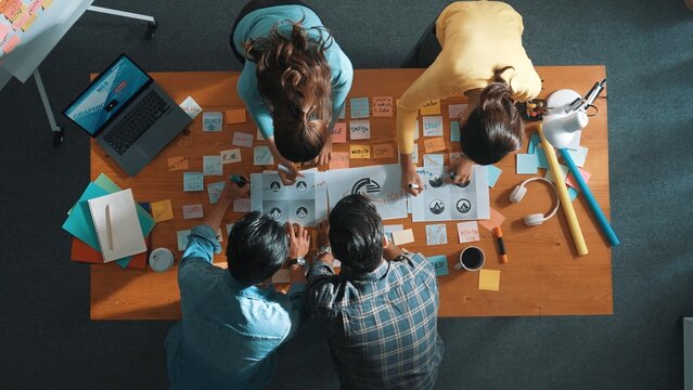 Top view of business team write graphic logo on meeting table with colorful sticky notes and design while explain idea. Project manager sharing idea and explain concept art to smart team. Symposium.