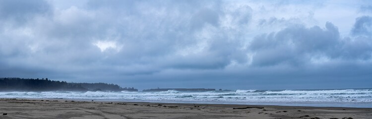 Fototapeta premium Panorama of stormy skies over Coos Head Beach with the Point Arago lighthouse in the distance near Charleston, Oregon, USA