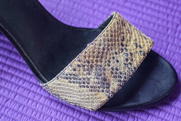 one gray black summer shoe made of fabric and leather with high heels stands on a purple table