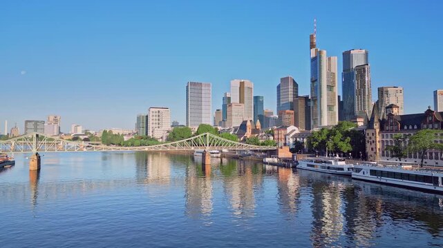 Aerial drone panning shot from Frankfurt Cathedral to the skyscraper skyline and Eiserner Steg bridge. 100m high panoramic view over the Main River and financial district in Frankfurt, Germany.