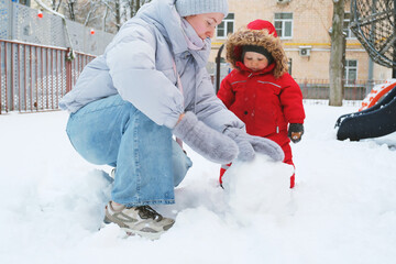 Child Making Snowball with Adult in Winter Scene