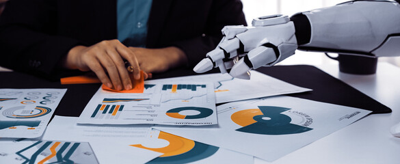Business Meeting with Artificial Intelligence and Data Analysis Charts on Table, Robotic Hand Assisting Human Professional with Reports and Graphics. Noogenesis