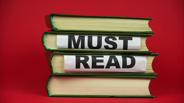 The phrase 'must read' appears from between books. Stop motion. A pile of books on red background. Stop motion