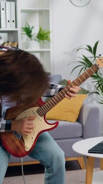 Cheerful man rocker playing electric guitar waving her hair. Bearded guy have fun jumping dancing and listening to music. People weekend evening leisure activities.