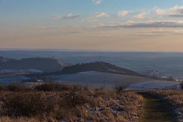 Panoramic view from Table Mountain to Mikulov and Holy Hill in winter. Picturesque Palava landscape with wind turbines on the horizon at sunset