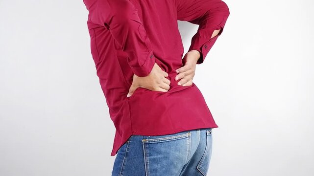 Man suffering from back pain at home. Bad posture problem.  holding his lower back with a pained expression, indicating back pain or discomfort. Osteoporosis.Health and medical care concepts