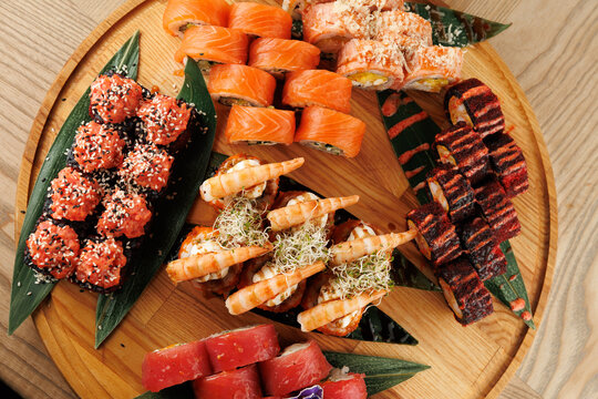 Explore a variety of sushi dishes from different styles and flavors beautifully arranged on a wooden platter