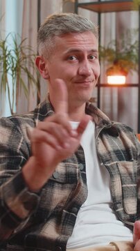 Displeased upset man with gray hair reacting to unpleasant awful idea dissatisfied with bad quality wave hand shake head No dismiss idea, dont like proposal at home. Young guy sitting in room on couch