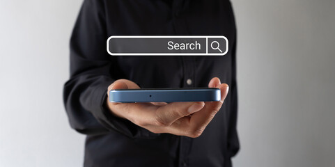 A person is holding a cell phone with the web search bar icon floating on the screen.