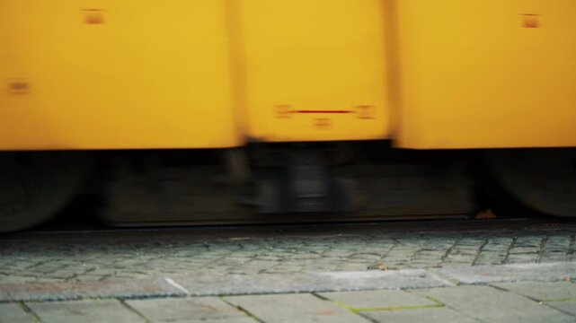 Two trams passing on parallel tracks with visible wheels, showing synchronized urban transport