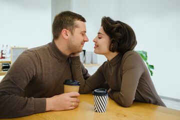 Loving couple shares a tender kiss at a cafe table during a cozy, intimate date