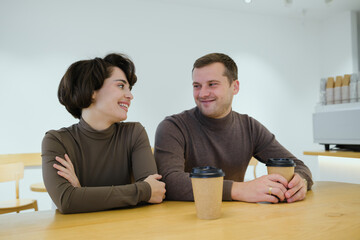 Couple enjoying coffee together at a bright cafe, sharing smiles and friendly conversation