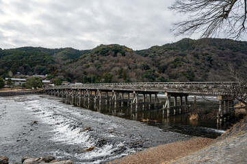 Togetsukyo Bridge in winter: Peaceful scenery of Katsura River and mountains in Arashiyama, Kyoto - No people.