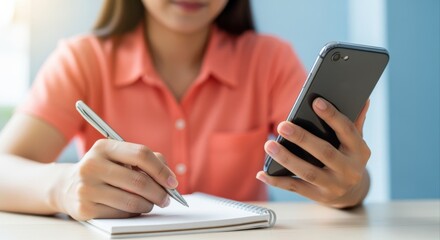 Woman Planning and Writing in Notebook While Holding Phone, Balancing Digital and Traditional Methods