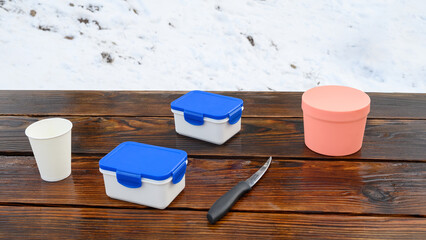 set of food containers and a paper cup on a dark wooden table in winter