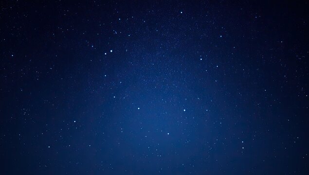 Deep, blue night sky speckled with countless, faint stars and hazy texture