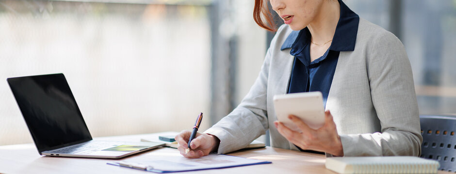 Serious and focused financial accounting on paper work inside office, mature woman using calculator and laptop for calculating reports and summarizing accounts, businessman at work in casual clothes