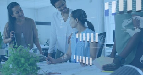 Reviewing four women wearing workwear at office, marking plans with pens, plant left, data overlays