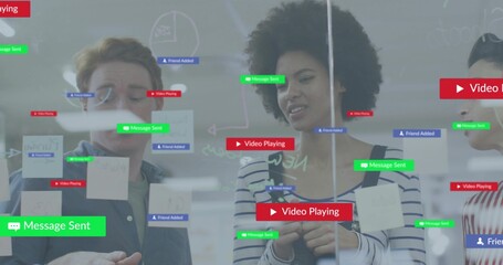 Discussing plan, three staff in denim and stripes writing on glass wall, markers Post-its overlays