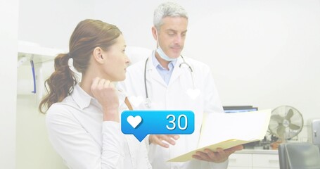 Explaining physician and patient holding chart in clinic, with coat stethoscope and blue heart 30