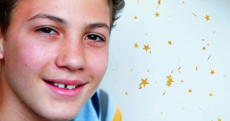Smiling boy facing camera at studio, wearing blue top with yellow stripe and gold star decals