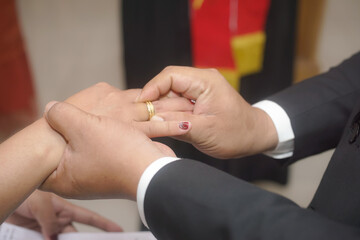 Bride placing wedding ring on groom's finger during ceremony