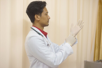 Male Doctor Preparing for Examination by Donning Sterile Medical Gloves