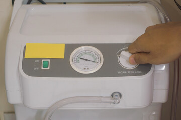 Hand Adjusting a Vacuum Regulator on a Medical Device.  Modern medical suction machine for hospital use