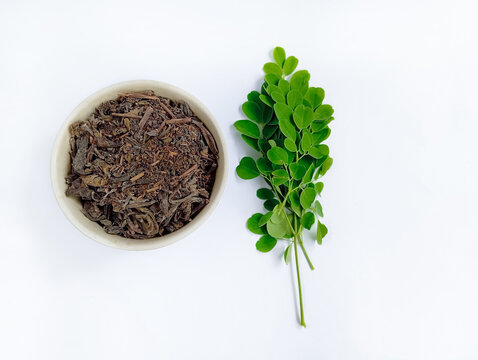 Dry Moringa leaf tea or kelor in a small bowl, isolated on a white background, herbal drink, healthy lifestyle