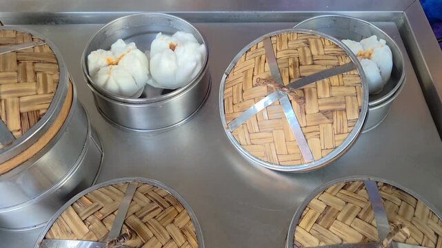 Top-down view of steaming dim sum baskets arranged on a metallic preparation surface.