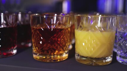 Bartender working, beautiful row line of different coloured liquor alcohol cocktails on a party in a bar, catering banquet on event, barman mixing drinks, selection of beverages in a restaurant club