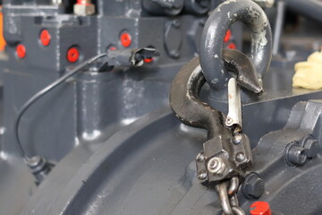 Close up of a heavy duty steel lifting hook attached to a large industrial engine block, professional mechanical equipment for lifting and moving heavy machinery in a factory.