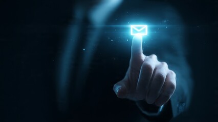 Business professional's finger touches glowing email icon on futuristic digital interface, symbolizing communication and connection