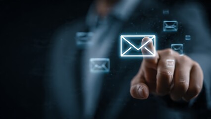Professional hand reaches out to touch glowing digital envelope icon on dark, futuristic background symbolizing communication and connection