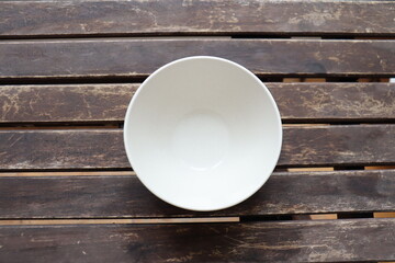Empty white bowl on an old wooden table. The price of food and the poverty. Cost of the living and dish. Dinner time and food choice. 